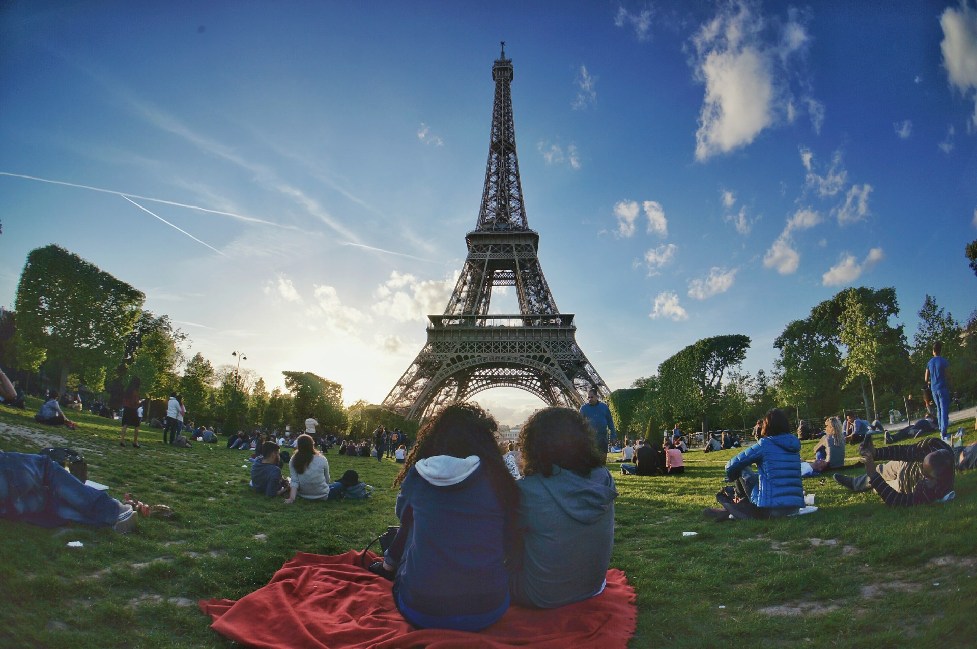 Junge Leute entspannen auf dem Rasen des Champ de Mars, im Hintergrund der Eiffelturm